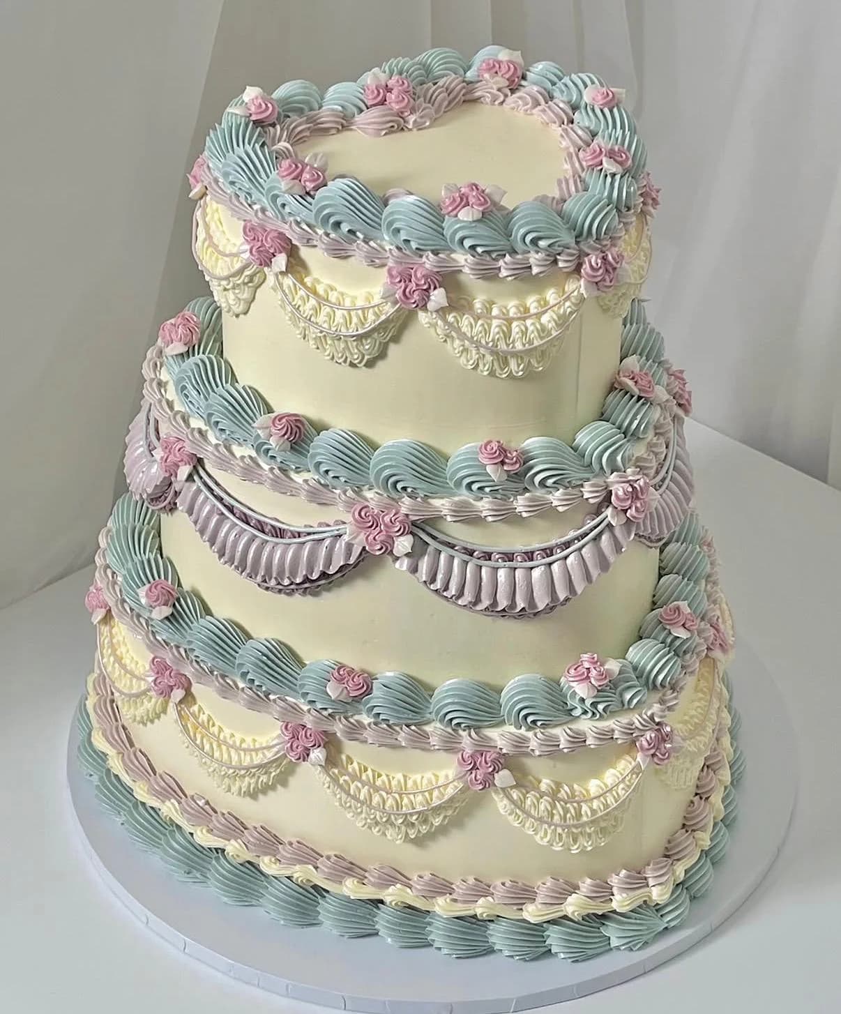Three-tier pastel wedding cake with intricate piping